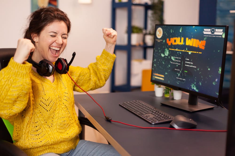 O jogador alegre comemora a vitoria do jogo de tiro espacial on line em um poderoso computador pessoal